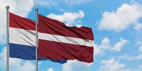 Netherlands and Latvia flag waving in the wind against white cloudy blue sky together. Diplomacy concept, international relations.