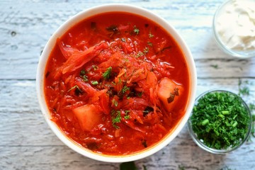 Ukrainian and Russian cuisine, red borsch. Tomato soup. Vegetable borscht made from tomato, bell pepper, parsley, onions, potatoes, carrots, cabbage and beets. Food on a wooden background. Food in a w
