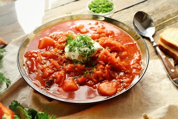 Ukrainian and Russian cuisine, red borsch. Tomato soup. Vegetable borscht made from tomato, bell pepper, parsley, onions, potatoes, carrots, cabbage and beets. Food on a wooden background.
