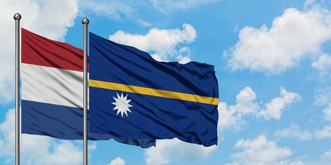 Netherlands and Nauru flag waving in the wind against white cloudy blue sky together. Diplomacy concept, international relations.