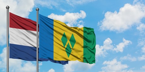 Netherlands and Saint Vincent And The Grenadines flag waving in the wind against white cloudy blue sky together. Diplomacy concept, international relations.
