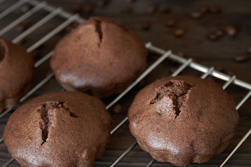Homemade chocolate muffins on metal oven grill with coffee beans. Dark wooden background, closeup, selective focus