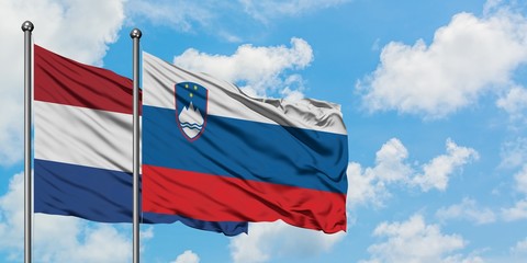 Netherlands and Slovenia flag waving in the wind against white cloudy blue sky together. Diplomacy concept, international relations.