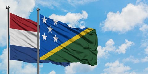 Netherlands and Solomon Islands flag waving in the wind against white cloudy blue sky together. Diplomacy concept, international relations.