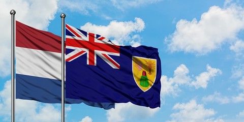 Netherlands and Turks And Caicos Islands flag waving in the wind against white cloudy blue sky together. Diplomacy concept, international relations.