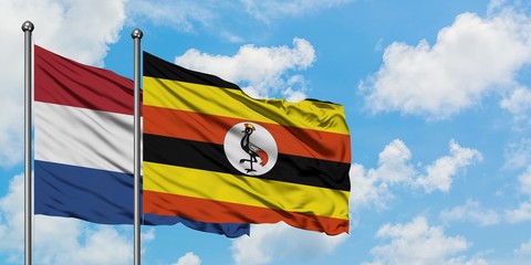 Netherlands and Uganda flag waving in the wind against white cloudy blue sky together. Diplomacy concept, international relations.