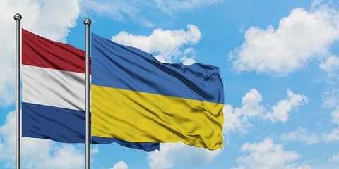 Netherlands and Ukraine flag waving in the wind against white cloudy blue sky together. Diplomacy concept, international relations.