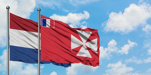 Netherlands and Wallis And Futuna flag waving in the wind against white cloudy blue sky together. Diplomacy concept, international relations.