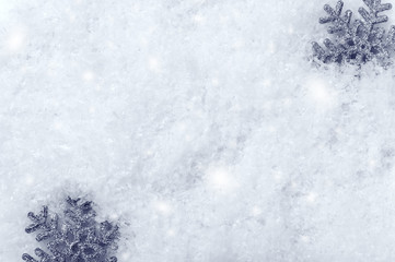 Silver snowflakes on snow top view background. Winter season backdrop with decorative toys on white...