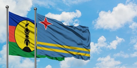 New Caledonia and Aruba flag waving in the wind against white cloudy blue sky together. Diplomacy concept, international relations.