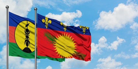 New Caledonia and Guadeloupe flag waving in the wind against white cloudy blue sky together. Diplomacy concept, international relations.