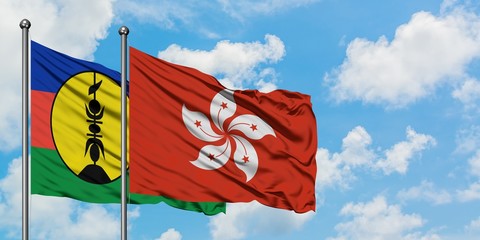 New Caledonia and Hong Kong flag waving in the wind against white cloudy blue sky together. Diplomacy concept, international relations.