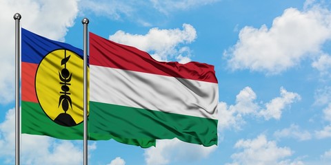 New Caledonia and Hungary flag waving in the wind against white cloudy blue sky together. Diplomacy concept, international relations.
