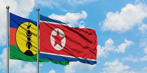 New Caledonia and North Korea flag waving in the wind against white cloudy blue sky together. Diplomacy concept, international relations.