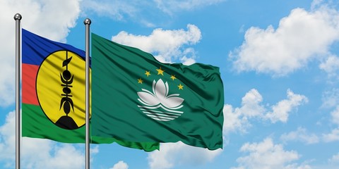 New Caledonia and Macao flag waving in the wind against white cloudy blue sky together. Diplomacy concept, international relations.