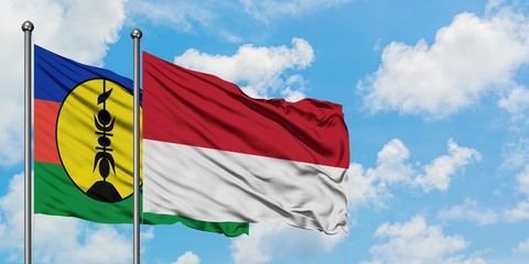 New Caledonia and Monaco flag waving in the wind against white cloudy blue sky together. Diplomacy concept, international relations.