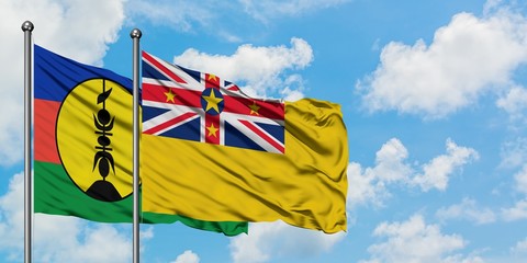 New Caledonia and Niue flag waving in the wind against white cloudy blue sky together. Diplomacy concept, international relations.