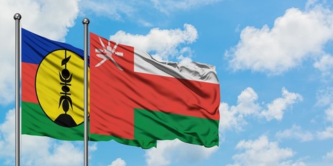 New Caledonia and Oman flag waving in the wind against white cloudy blue sky together. Diplomacy concept, international relations.