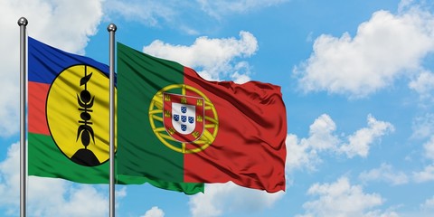New Caledonia and Portugal flag waving in the wind against white cloudy blue sky together. Diplomacy concept, international relations.