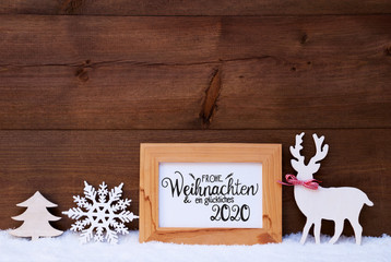 German Calligraphy Frohe Weihnachten Und Ein Glueckliches 2020 Mean Merry Christmas And Happy 2020. White Christmas Ornament Like Snowflake, Tree And Wooden Deer. Wooden Background With Snow