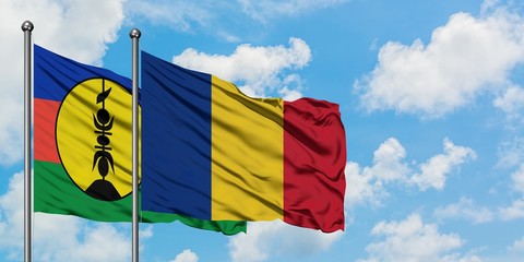 New Caledonia and Romania flag waving in the wind against white cloudy blue sky together. Diplomacy...