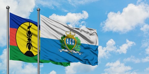New Caledonia and San Marino flag waving in the wind against white cloudy blue sky together. Diplomacy concept, international relations.