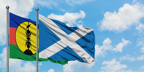 New Caledonia and Scotland flag waving in the wind against white cloudy blue sky together. Diplomacy concept, international relations.