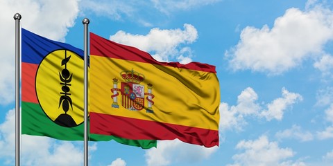 New Caledonia and Spain flag waving in the wind against white cloudy blue sky together. Diplomacy concept, international relations.