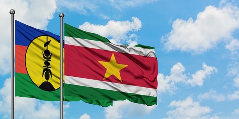 New Caledonia and Suriname flag waving in the wind against white cloudy blue sky together. Diplomacy concept, international relations.