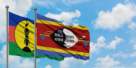 New Caledonia and Swaziland flag waving in the wind against white cloudy blue sky together....