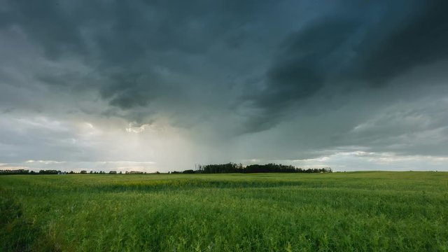 Rain storm above farmers field with light rays shining through 4K timelapse