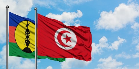 New Caledonia and Tunisia flag waving in the wind against white cloudy blue sky together. Diplomacy concept, international relations.
