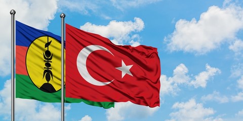New Caledonia and Turkey flag waving in the wind against white cloudy blue sky together. Diplomacy concept, international relations.