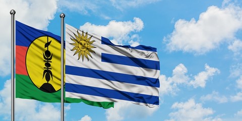 New Caledonia and Uruguay flag waving in the wind against white cloudy blue sky together. Diplomacy concept, international relations.