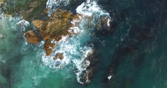 Top down 4K shot of waves breaking onto rocks in the ocean. Filmed in Laguna Beach, California.