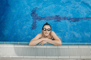 young woman swims in sports glasses in the pool