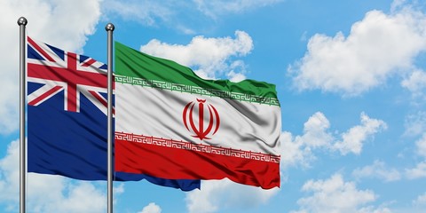 New Zealand and Iran flag waving in the wind against white cloudy blue sky together. Diplomacy...