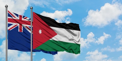 New Zealand and Jordan flag waving in the wind against white cloudy blue sky together. Diplomacy...