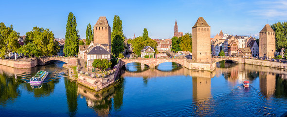 Panoramic view of the Ponts Couverts on the river Ill at the entrance of the Petite France historic quarter in Strasbourg, France, with a tour boat and an electric renting boat cruising on the canals. - obrazy, fototapety, plakaty