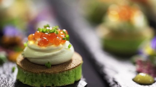 Closeup view of decorated rows of delicious, tasty and cute looking various canapes placed on table with white tablecloth for catering party somewhere in restaurant.