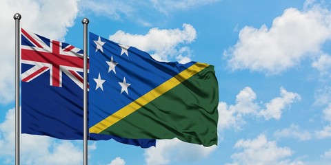 New Zealand and Solomon Islands flag waving in the wind against white cloudy blue sky together....