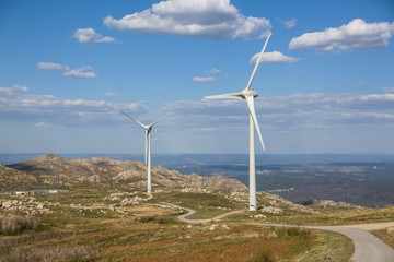 Fototapeta na wymiar View of a wind turbines on top of mountains, blue sky as background
