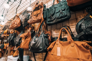 Female leather bags on wall in shop, accessories for women sale.