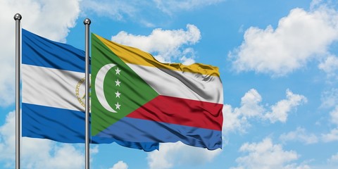 Nicaragua and Comoros flag waving in the wind against white cloudy blue sky together. Diplomacy...
