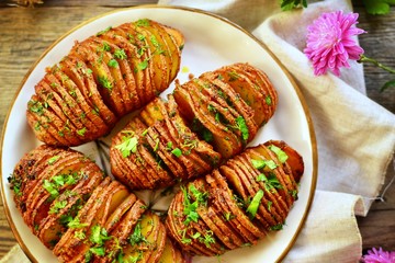 Appetizing potato accordion baked in the oven. Potato on a wooden background.  Hasselback potatoes....