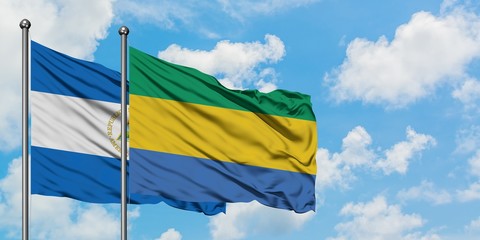 Nicaragua and Gabon flag waving in the wind against white cloudy blue sky together. Diplomacy...