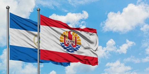 Nicaragua and French Polynesia flag waving in the wind against white cloudy blue sky together. Diplomacy concept, international relations.