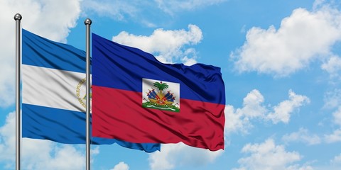 Nicaragua and Haiti flag waving in the wind against white cloudy blue sky together. Diplomacy...