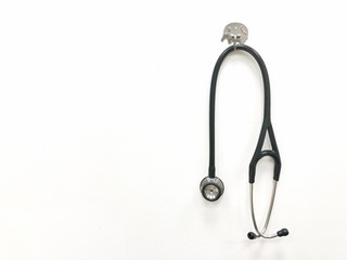 A black sthethoscope hanging on the white wall