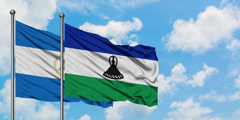 Nicaragua and Lesotho flag waving in the wind against white cloudy blue sky together. Diplomacy...